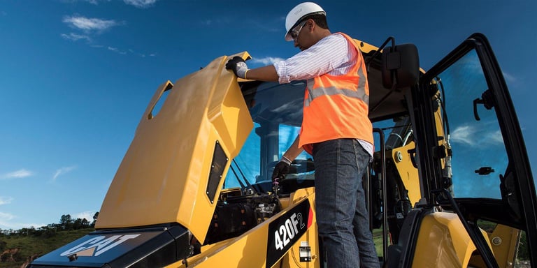 Technician performs routine maintenance on Cat 420F.